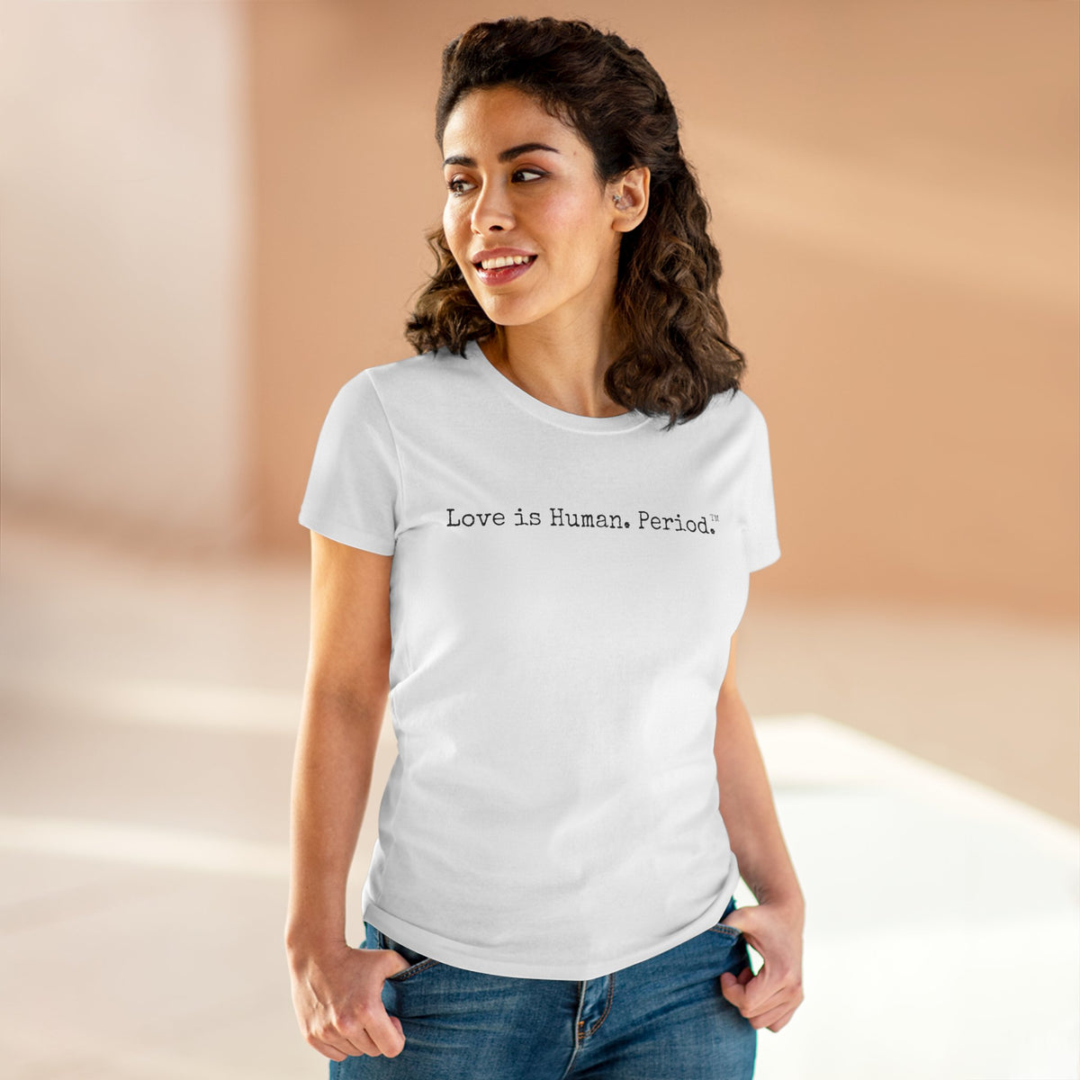 Woman wearing a white t-shirt with Love is human text on a beige background