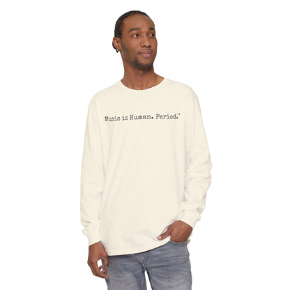 Man wearing cream long-sleeve shirt with text "Music is Human.Period" in clean type-writer font on white background.