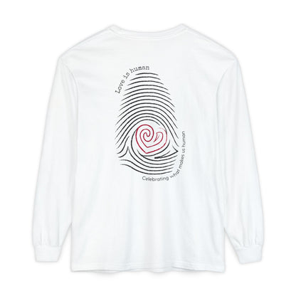A white long-sleeve t-shirt shown from the back, featuring a graphic of a fingerprint made of black concentric lines with a red spiral heart in the center and black text reading 'Love is human' and 'Celebrating what makes us human'.