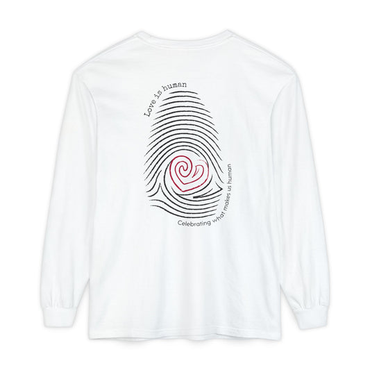 A white long-sleeve t-shirt shown from the back, featuring a graphic of a fingerprint made of black concentric lines with a red spiral heart in the center and black text reading 'Love is human' and 'Celebrating what makes us human'.