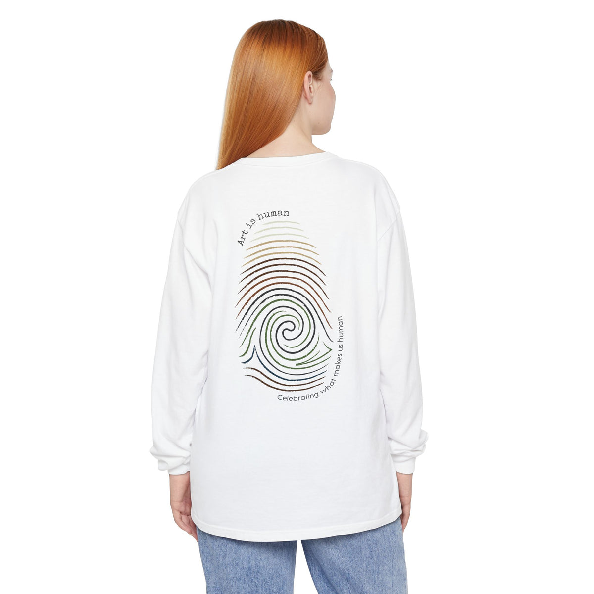 A woman with red hair is  wearing A white long-sleeve t-shirt shown from the back, featuring a colorful spiral fingerprint graphic with the text 'Art is human' and 'Celebrating what make us human'.