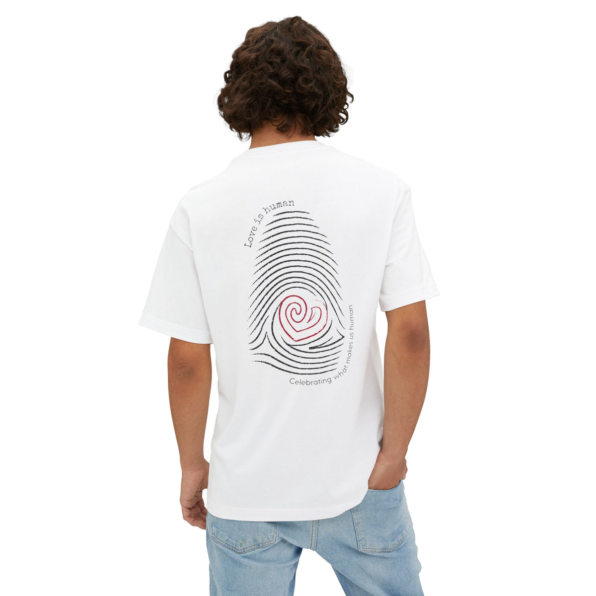 Person wearing a white t-shirt with text on the back,  featuring a graphic print of a fingerprint with a red heart center and black text reading 'Love is human' and 'Celebrating what makes us human'.