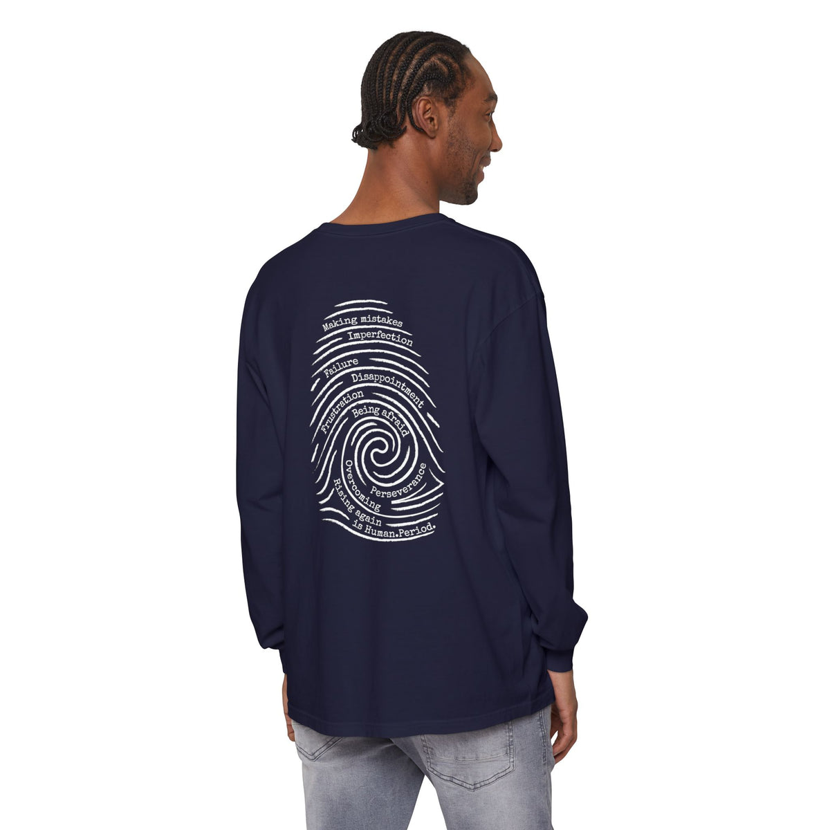Man wearing a navy blue long-sleeve t-shirt with a white graphic print of a spiral fingerprint on the back, set against a plain white background. Words like failure, making mistakes, perseverance and overcoming fill the spiral. 
