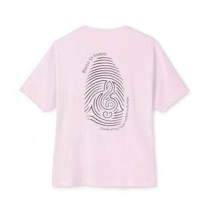 A light pink short-sleeve t-shirt shown from the back, featuring a black graphic of a fingerprint and musical notes with the text 'Music is human' and 'Celebrating music makes us human'.