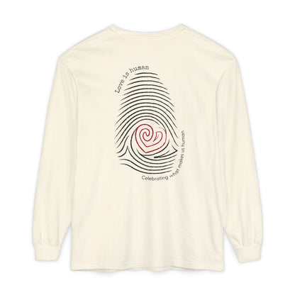 A cream long-sleeve t-shirt with a graphic on the back featuring a black fingerprint pattern, a red heart in the center, and black text that reads 'Love is human' and 'Celebrating what makes us human'.