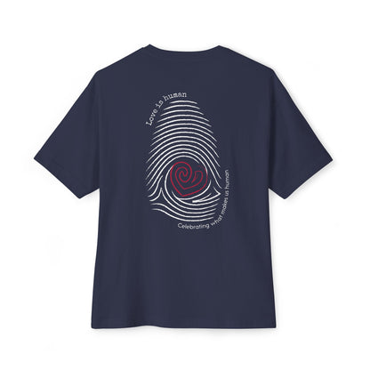 A navy blue short-sleeve t-shirt shown from the back, featuring a graphic print of a fingerprint with a red heart center and text reading 'Love is human' and 'Celebrating what makes us human'.