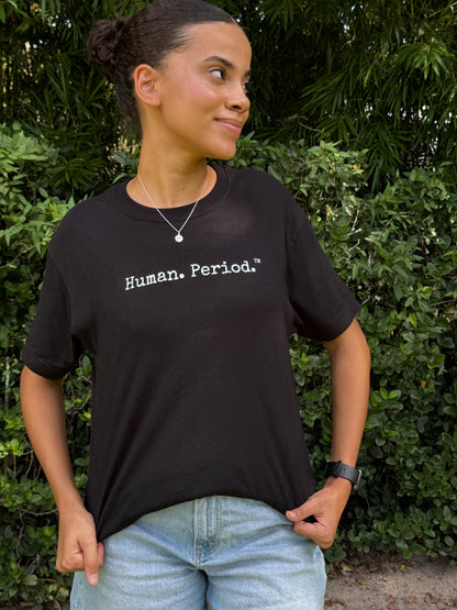 A woman wearing a black short-sleeve t-shirt with the text 'Human. Period.