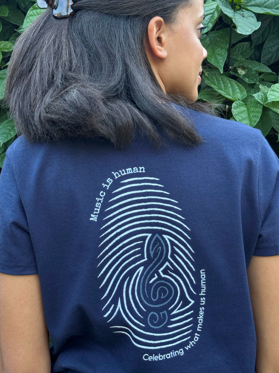 Blue t-shirt with music is human and celebrating what makes us human text.  White fingerprint design with blue treble clef.